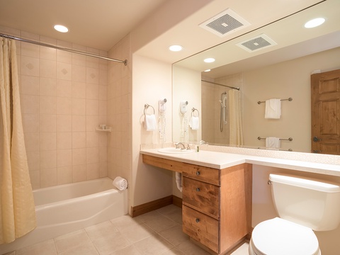 Your spacious bathroom features warm wood accents, a relaxing soaking tub, and a vanity with ample counter space—everything you need to unwind after a day of adventure.