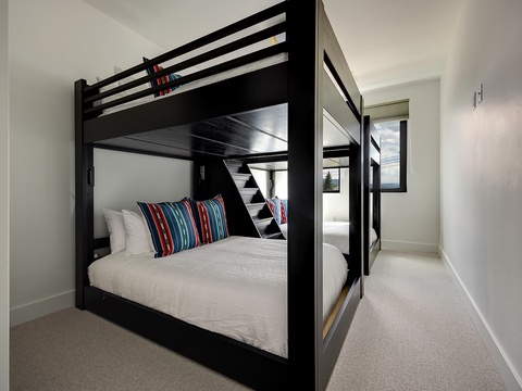 This clever bunk room maximizes space without sacrificing comfort, with sturdy modern bunks dressed in crisp linens and colorful accent pillows that bring a cozy, welcoming touch to your mountain getaway.