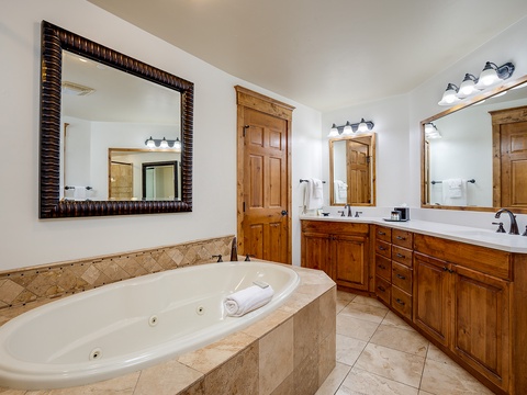 Unwind in your spa-style bathroom featuring a jetted soaking tub, dual vanities, and warm wood accents that invite relaxation after a day of adventure.