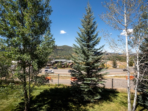 The property sits in a peaceful neighborhood surrounded by evergreen and aspen trees, with mountain views framing the quiet street beyond.