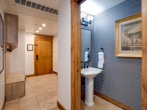 Step inside to find warm wood tones, elegant artwork, and a modern bathroom with sleek tilework and a pedestal sink—thoughtful details creating a welcoming retreat after your mountain adventures.