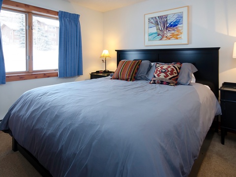 Sink into crisp, soft bedding under warm lamplight, where colorful pillows and mountain views greet your mornings in this cozy retreat.
