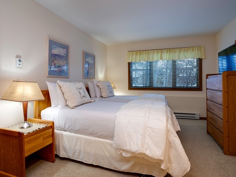 Sink into crisp white linens and wake to peaceful forest views through your window. This cozy bedroom features warm wood accents and thoughtful lighting for your perfect mountain retreat.