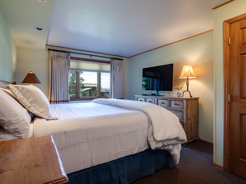 Sink into plush bedding and wake to natural light framing peaceful views. Your cozy retreat features warm wood accents, a flat-screen TV, and a tranquil palette that invites you to truly unwind.