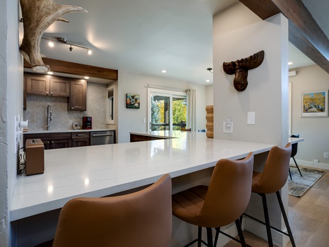 Gather at the sleek breakfast bar with mountain views streaming through sliding doors. Rustic beams and unique lodge-inspired accents create your perfect mountain retreat atmosphere.