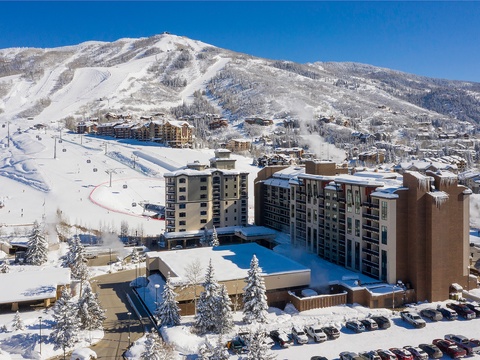 A premier ski resort village nestled at the base of snow-covered slopes, with ski lifts ascending the mountain, resort buildings blending into the winter landscape, and nearby lodging and amenities for a complete mountain getaway.