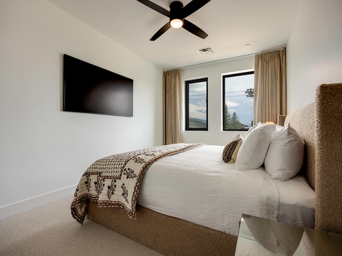Your peaceful retreat features a plush bed dressed in soft linens, a ceiling fan overhead, and stunning natural views framed by tranquil windows. Step outside or sink into these crisp sheets—pure relaxation awaits.