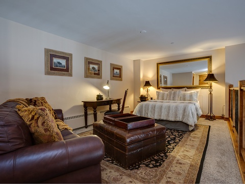 Unwind in your elegant suite featuring a plush queen bed, luxurious leather seating, and warm ambient lighting that creates a cozy retreat after a day of adventure.