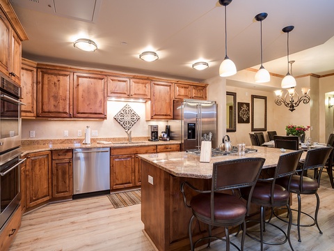 Your spacious kitchen awaits with warm wood cabinetry, granite countertops, and stainless steel appliances. Gather at the expansive island for morning coffee or evening meals under elegant pendant lighting.