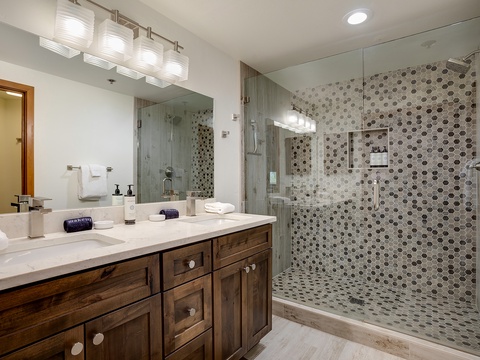 Slip into relaxation in your spacious walk-in shower with modern hexagonal tiling and dual showerheads, or freshen up at the double vanity with warm wood cabinetry.