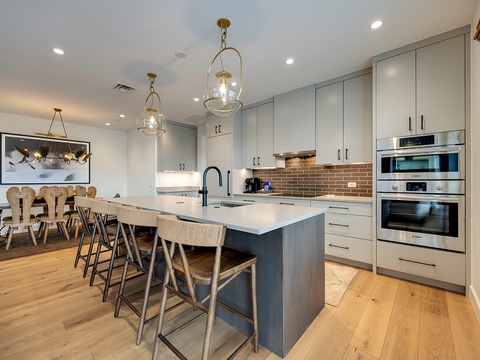 Step into your modern chef's kitchen, fully equipped with sleek stainless appliances and an elegant island perfect for morning coffee or gathering with friends over a home-cooked meal.