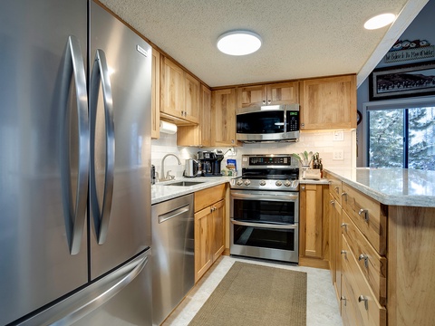 Step into your fully-equipped kitchen with warm wood cabinetry, stainless steel appliances, and granite countertops—perfect for preparing your favorite meals. The coffee maker and oven are ready for your morning routine and home-cooked dinners alike.