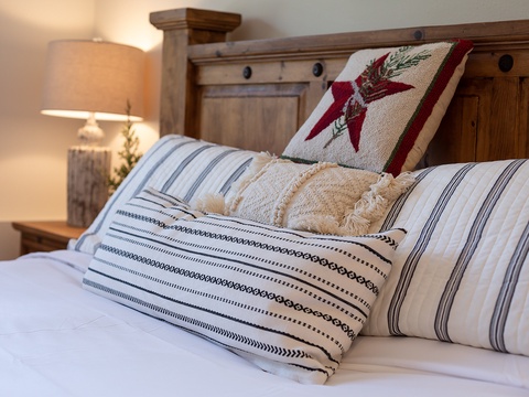 Sink into crisp linens and plump pillows after a day of adventure. The rustic wooden headboard and warm bedside lamp create your personal retreat.