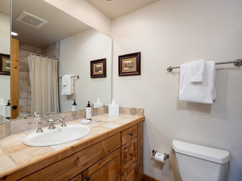 Your private bathroom features a spacious vanity with warm wood cabinetry, plush towels, and a relaxing shower space—perfectly set for unwinding after your mountain adventures.