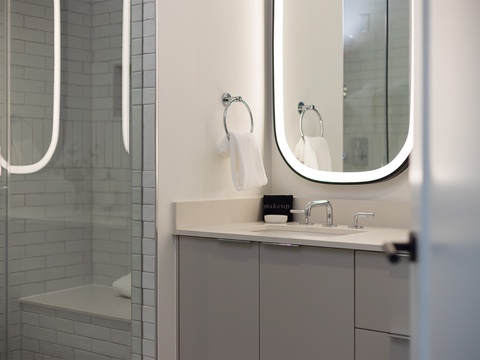 Step into your private sanctuary—a modern bathroom with a sleek vanity, illuminated mirror, and pristine white subway tile shower waiting to refresh you.