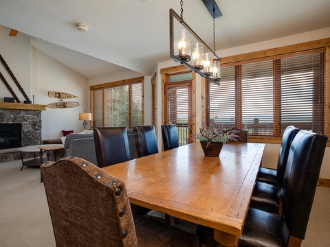 Gather with your group at the handcrafted wood dining table, warmed by the stone fireplace and bathed in natural light from floor-to-ceiling windows overlooking the mountains.