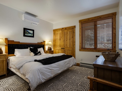 Sink into crisp linens in your cozy bedroom, where rustic wood accents, soft lighting, and climate-controlled comfort await after a day of mountain adventure.