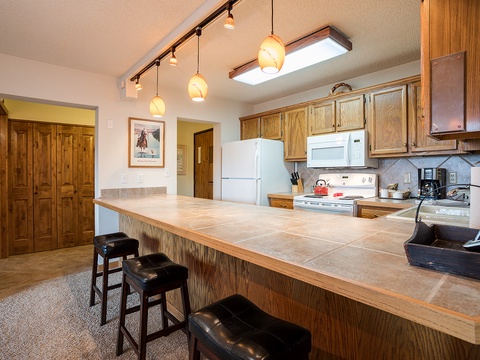 Gather around the spacious kitchen island, perfect for morning coffee or preparing homemade meals together. Warm wood accents and ample counter space create an inviting hub for your vacation memories.