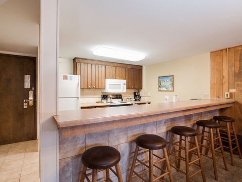 Your spacious kitchen features warm wood cabinetry, full appliances, and a generous breakfast bar where you can gather with loved ones over morning coffee or casual meals together.