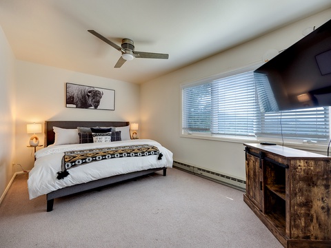 Slip into this cozy bedroom with rustic touches and modern comfort—crisp linens, soft lighting, and a ceiling fan await your restful mountain escape.
