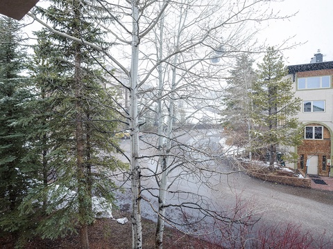 Multi-level vacation rental property surrounded by mature evergreen and deciduous trees, with convenient paved driveway access and spacious parking area for guest vehicles.