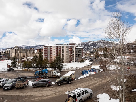 Winter mountain resort area with lodging buildings and snowy peaks visible in the surrounding landscape.