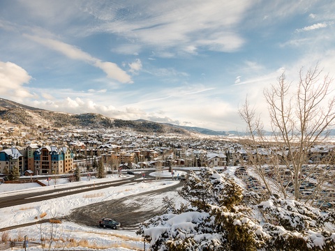 A winter mountain town nestled in a snowy valley, surrounded by forested slopes and framed by clear blue skies—offering a peaceful retreat in nature's seasonal embrace.