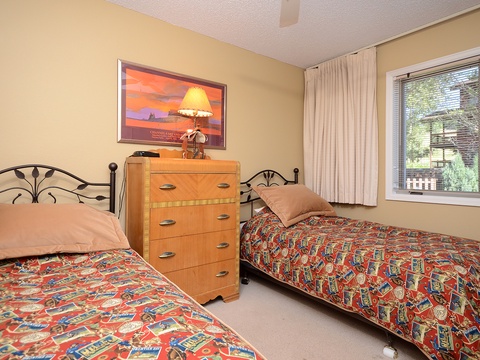 Your restful bedroom features two cozy twin beds with vibrant southwestern-style bedding and a warm golden glow, perfect for peaceful mountain getaways.