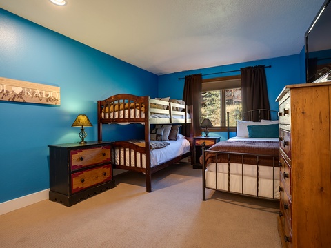 Your group will love this spacious bedroom with a bunk bed and separate twin, perfect for kids or friends traveling together. Bright blue walls, wood furniture, and a window with mountain views create a cozy alpine retreat.