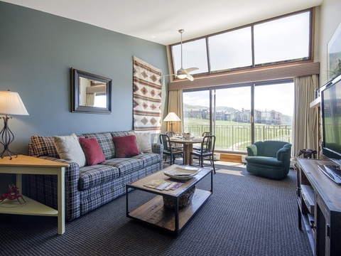 Settle into your cozy living room and enjoy expansive golf course views through floor-to-ceiling windows, perfect for unwinding after a day of mountain adventures.