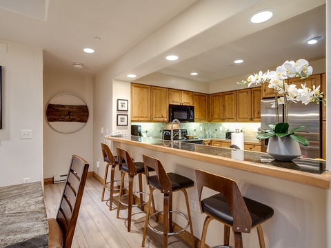 Gather at the warm wood breakfast bar where modern style meets mountain charm, perfect for morning coffee or casual meals with friends.