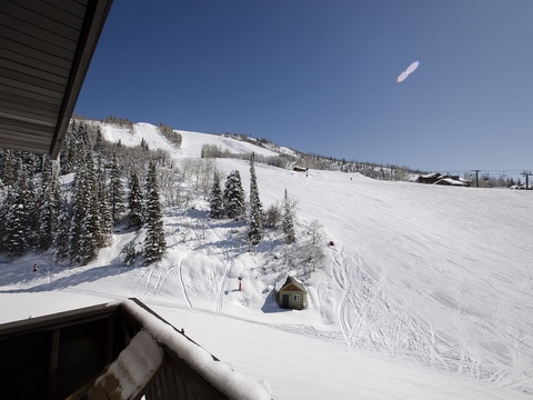 Snow-covered slopes and evergreen forests create a picturesque alpine setting just beyond the property, with ski runs and chairlifts visible in the surrounding mountain landscape.
