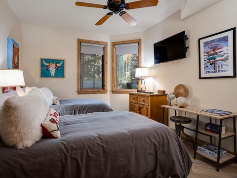 Sink into cozy twin beds with plush throws and pillows. Natural light spills in through double windows, and your mountain-themed TV setup awaits for relaxed evenings.