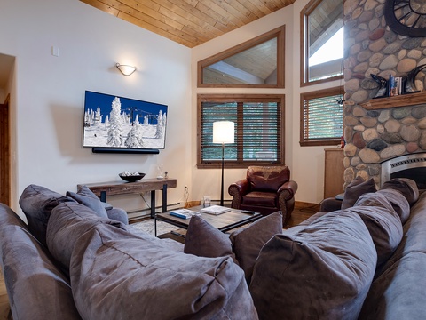 Sink into plush seating by your stone fireplace, where vaulted wood ceilings and mountain views create your perfect retreat after a day of adventure.