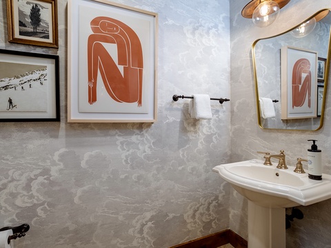 Freshen up in your stylish bathroom, where artistic touches and elegant brass fixtures create a refined, welcoming space for your morning routine.
