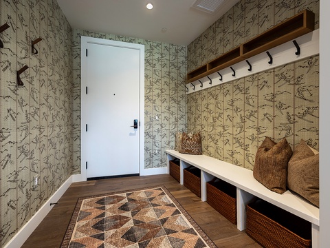 A welcoming entryway with built-in bench, woven storage baskets, and charming woodland-themed wallpaper creates your perfect spot to settle in after exploring the area.