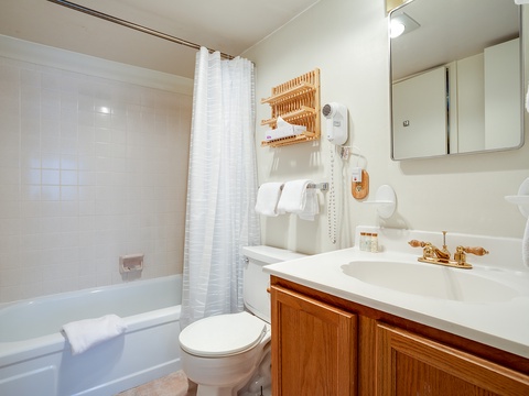 Your spotless private bathroom features crisp white tile, warm wooden accents, and thoughtful touches like a hairdryer and fresh towels, making your stay effortlessly comfortable.