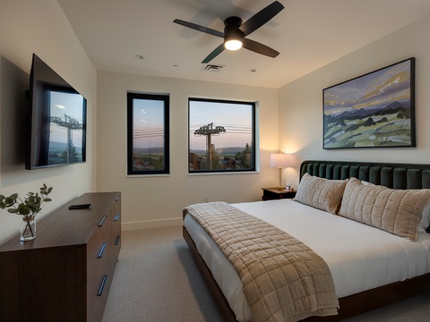 Drift off in your serene bedroom with soft linens, modern furnishings, and windows framing peaceful neighborhood views. The ceiling fan keeps you comfortable while artwork and warm lighting create a welcoming retreat.