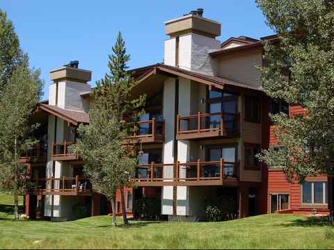 A multi-level mountain property with private balconies, stone fireplaces, and warm wood accents, set among aspens and evergreens on manicured grounds.