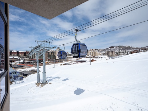 A ski resort gondola glides above snow-covered slopes with mountain village buildings dotting the landscape—a scenic winter destination offering convenient access to skiing adventures.
