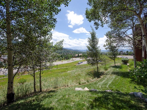 The property sits in a tranquil mountain setting, framed by aspen trees and rolling hills, with a scenic view of the surrounding valley and distant peaks.