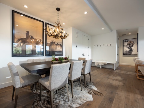 Gather around the stunning dark wood table under a dramatic antler chandelier, where memorable meals and conversations await in your elegant dining space.