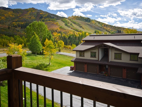 A mountain property nestled in a scenic alpine valley with autumn foliage, adjacent ski slopes, and convenient garage access for guests arriving to explore the surrounding natural landscape.