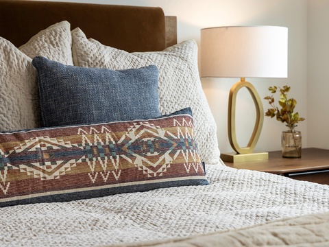 Sink into plush layers of comfort with textured linens, patterned pillows, and warm bedside lighting that creates your perfect retreat after a day of exploring.