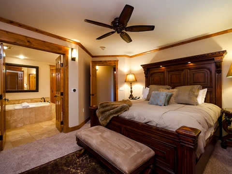 Retreat to your elegant primary suite with rich wood furnishings, plush bedding, and a luxurious en-suite bath. Cozy lighting and a ceiling fan keep you comfortable year-round.