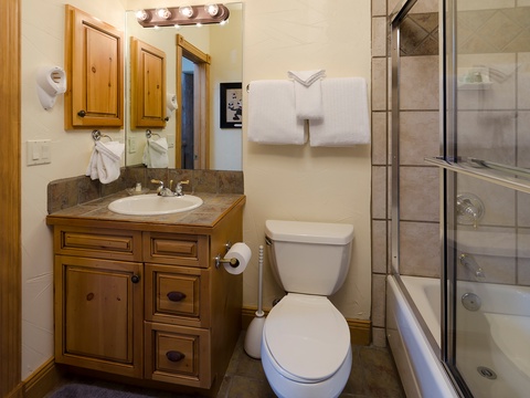 Your private bathroom features warm wood accents, plush towels, a spacious vanity, and a walk-in shower—everything you need to refresh after your adventures.