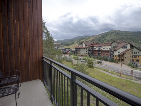 A mountain resort town with forested slopes and multi-story lodges nestled at the base of rolling peaks.