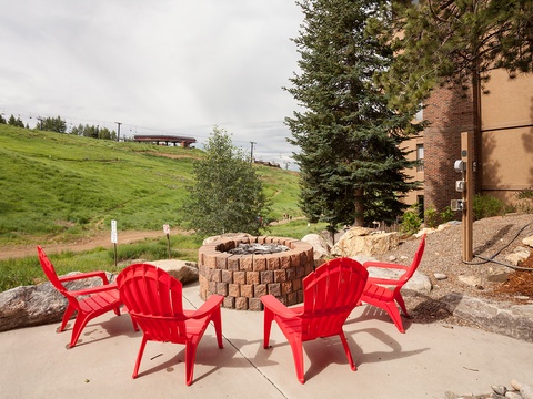Gather around the stone firepit in vibrant red Adirondack chairs, where hillside views and mountain breezes set the scene for unforgettable evenings under the open sky.