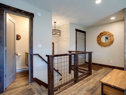 This bright, open hallway welcomes you with warm wood accents, stylish lighting, and a unique gold-leaf mirror that adds a touch of elegance to your mountain retreat.