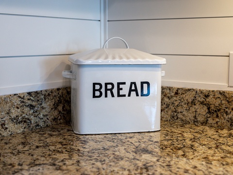 A charming bread box rests on your granite countertop, adding a cozy touch to your fully-equipped kitchen space where you can whip up your favorite meals.